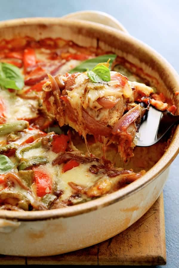 Close-up photo of Italian Sausage and Bell Pepper Polenta Bake with server pulling a cheesy spoonful from dish.