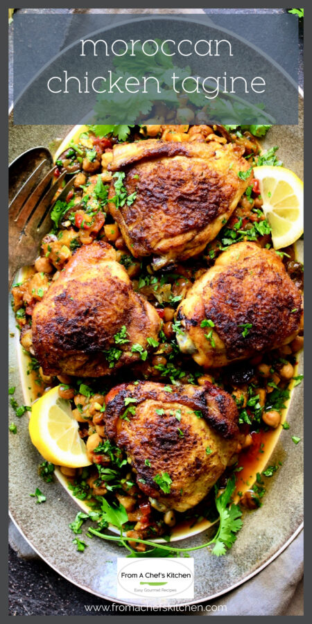 Four pieces of Moroccan Chicken Tagine on gray-rimmed platter garnished with lemon wedges and cilantro sprigs.