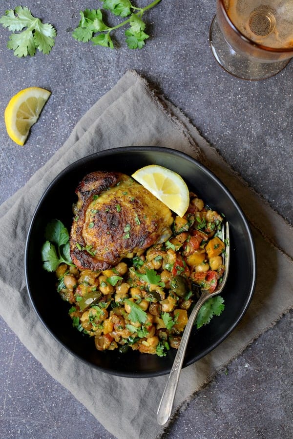 Photo of one serving of Moroccan Chicken Tagine with Butternut Squash, Chickpeas and Olives in black bowl.