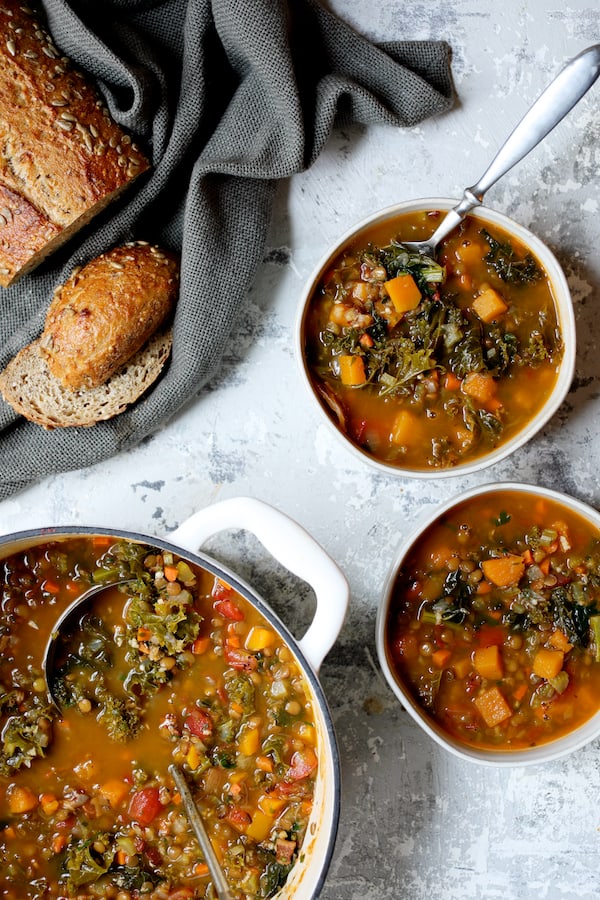Photo of Spicy Kale Butternut Squash and Lentil Soup with Bacon with soup served in two white soup bowls.