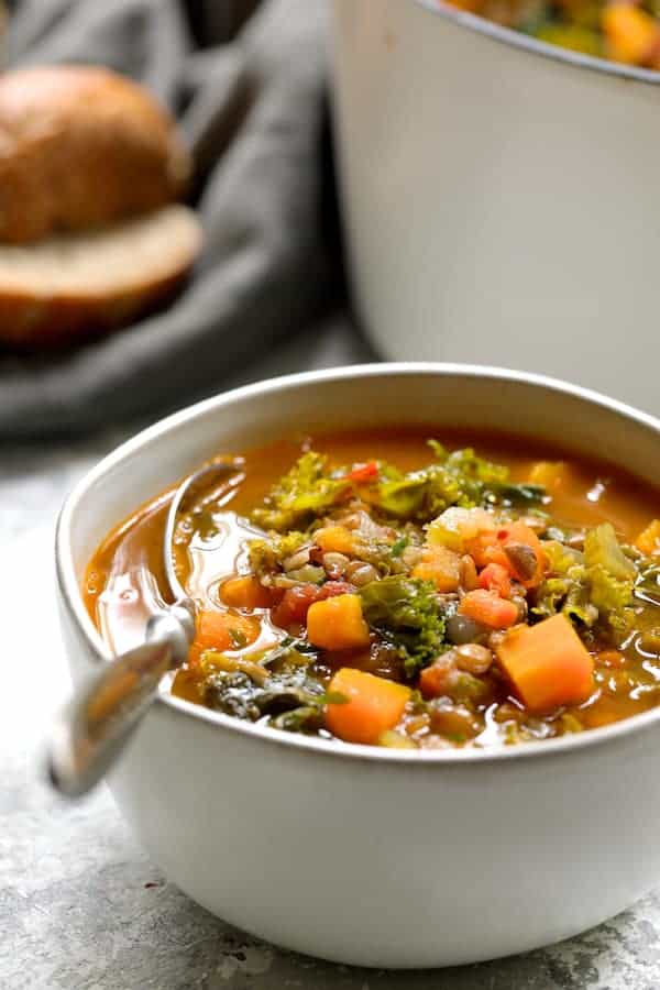 Photo of a serving of Spicy Kale Butternut Squash and Lentil Soup with Bacon in white bowl.