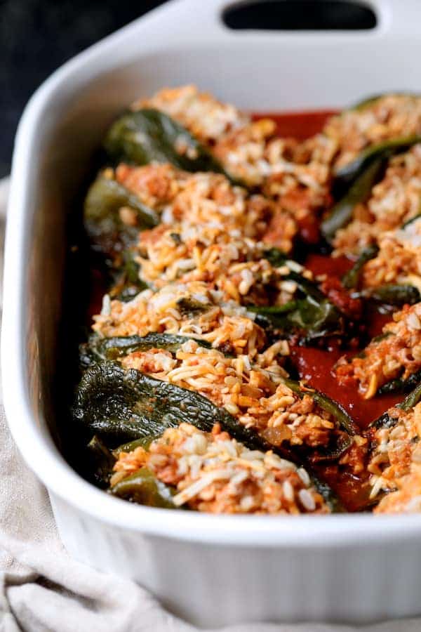Photo of stuffed peppers in white baking dish before being sauced and baked.