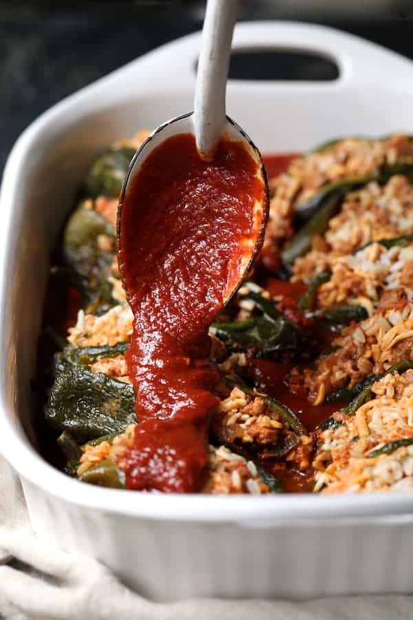 Photo of sauce being spooned over stuffed peppers.