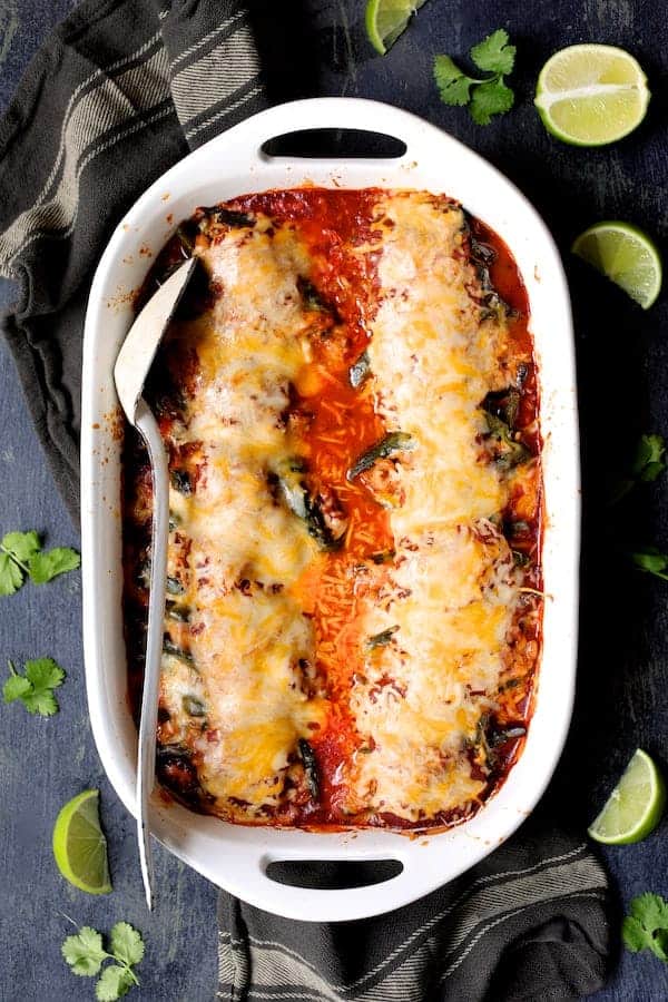 Photo of Chorizo and Brown Rice Stuffed Poblano Peppers in white baking dish garnished with limes and cilantro sprigs.