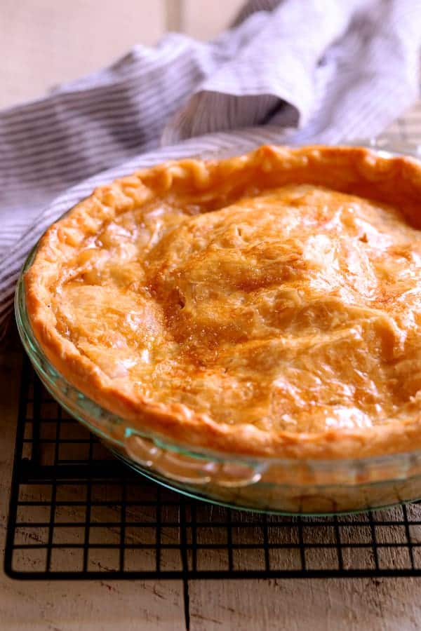 Photo of baked apple pie on cooling rack.