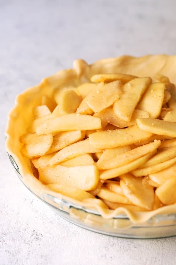 Photo of sliced apples in pie crust in the pan before placing the top crust over pie.