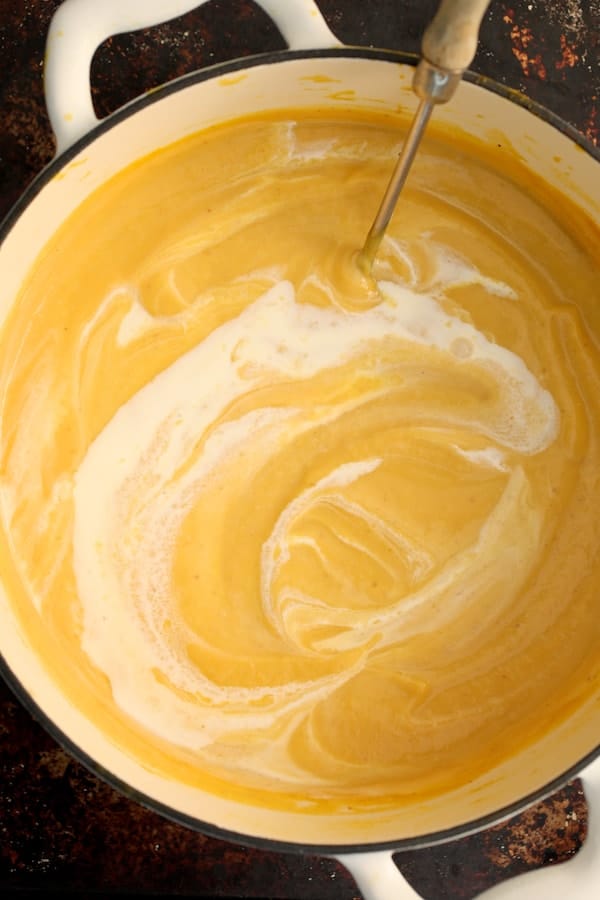 Photo of Pumpkin Soup with Marsala and Mascarpone in Dutch oven being stirred with a ladle.