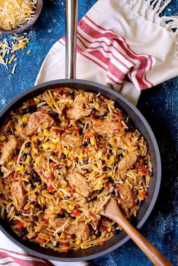 Chicken, Orzo and Black Bean Skillet in the skillet being stirred with wooden spoon.