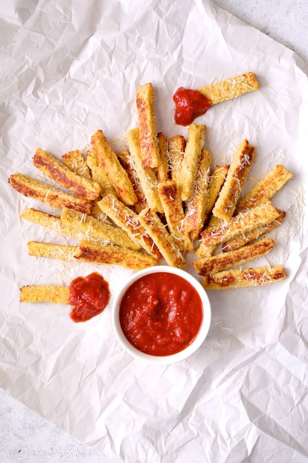 Photo of Spaghetti Squash Fries on white paper with marinara sauce.