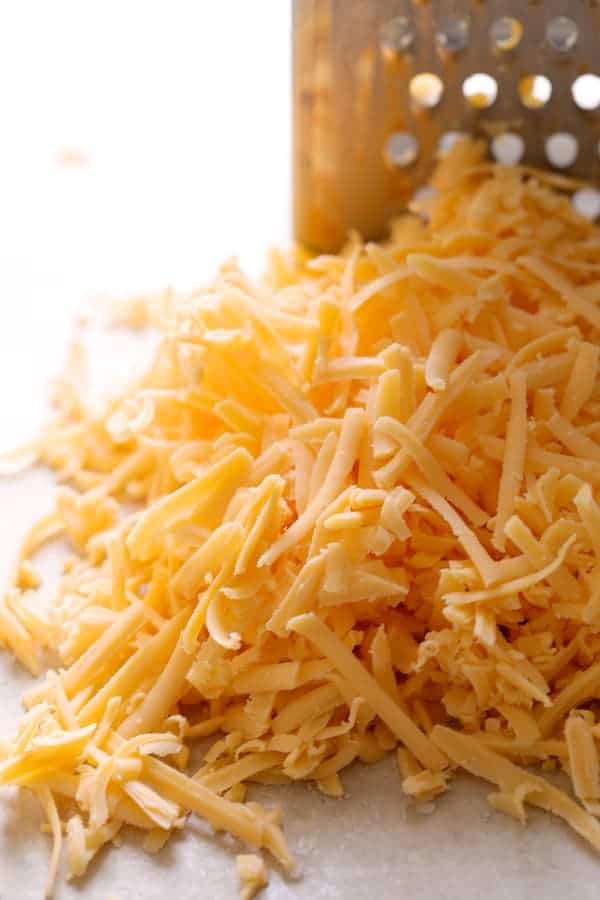 Photo of a pile of freshly shredded cheddar cheese.