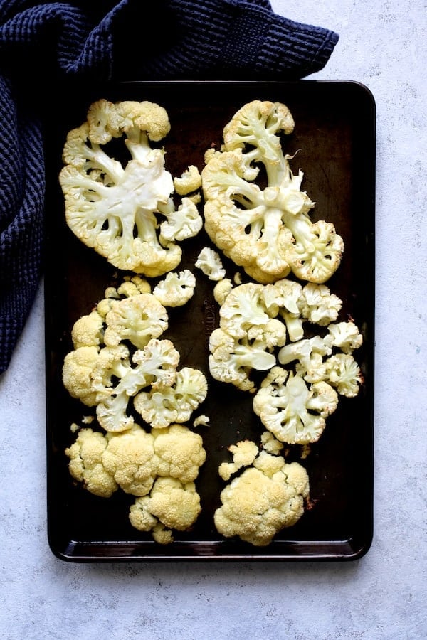 Photo of cauliflower steaks on baking sheet after being roasted.