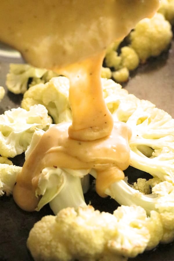 Photo of cheese sauce being poured onto cauliflower.
