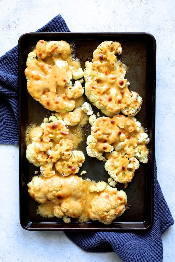 Photo of cheese-covered broiled cauliflower steaks on baking sheet.