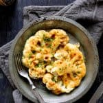 Cauliflower Welsh Rarebit in metal pie pan with fork on gray napkin.