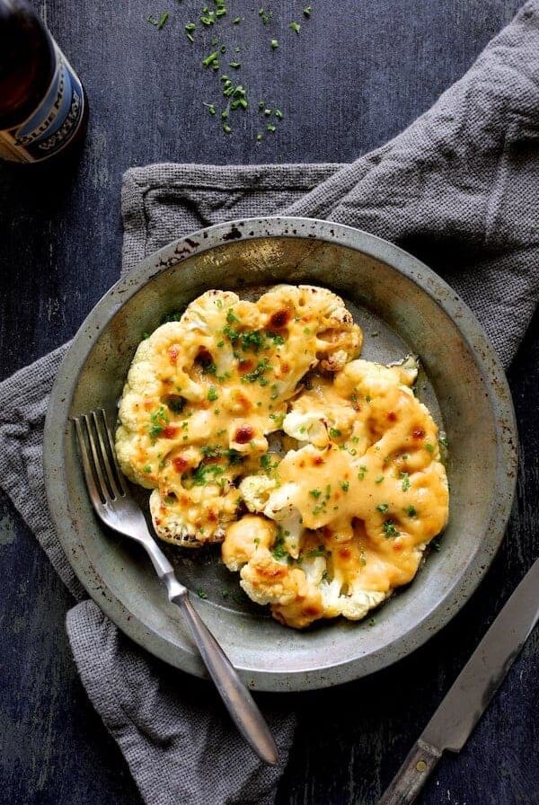Cauliflower Welsh Rarebit in metal pie pan with fork on gray napkin.