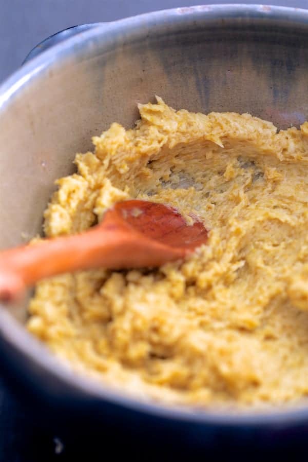 Photo of green curry butter being mixed up in a bowl with wooden spoon.