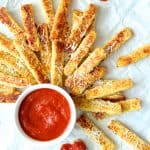 Spaghetti Squash Fries on white paper with marinara sauce.