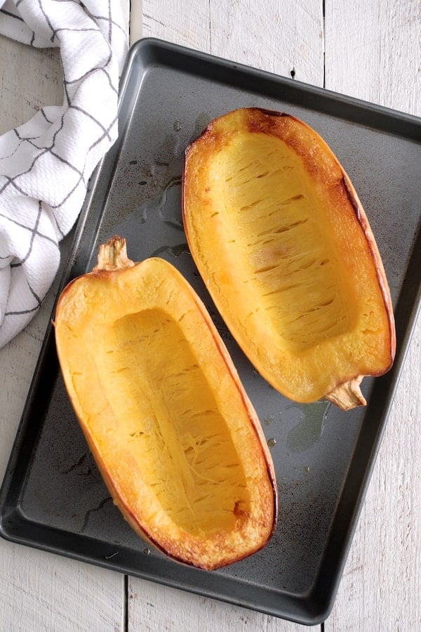 Photo of two cooked spaghetti squash halves on baking sheet.