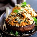 Two Barley Risotto-Stuffed Portobello Mushrooms on cast iron steak plate.