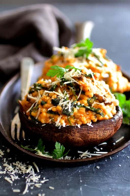 Two Barley Risotto-Stuffed Portobello Mushrooms on cast iron steak plate.
