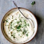 Cauliflower White Bean Puree in earthenware bowl garnished with chopped fresh parsley.