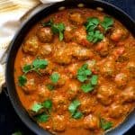 Meatballs in Spicy Curry in skillet with yellow striped towel.