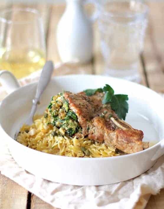 Photo of Sicilian-Stuffed Pork Chops with White Wine Caper Sauce and orzo on white plate.