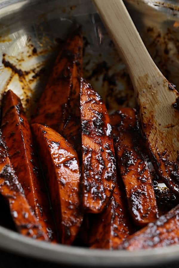 Photo of sweet potato wedges tossed with harissa paste before being roasted.