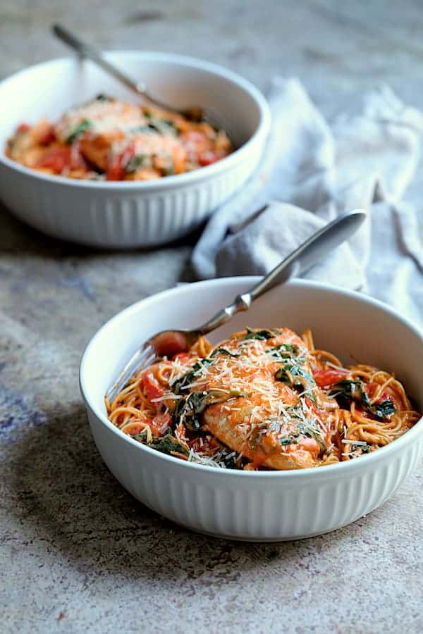 Photo of two servings of Chicken in Rosa Sauce with Roasted Red Bell Pepper and Spinach on gray background.