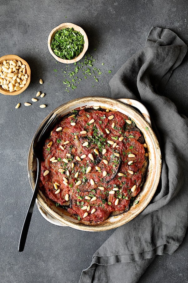 Photo of Turkish Eggplant Casserole - Imam Bayildi on gray background with gray towel.