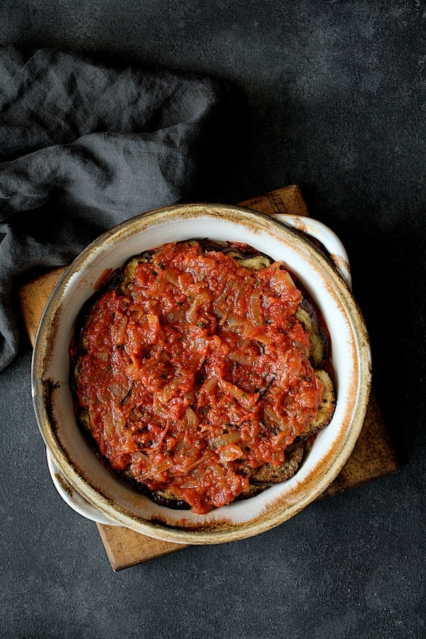 Photo of final later of tomato sauce placed over the top in baking dish.