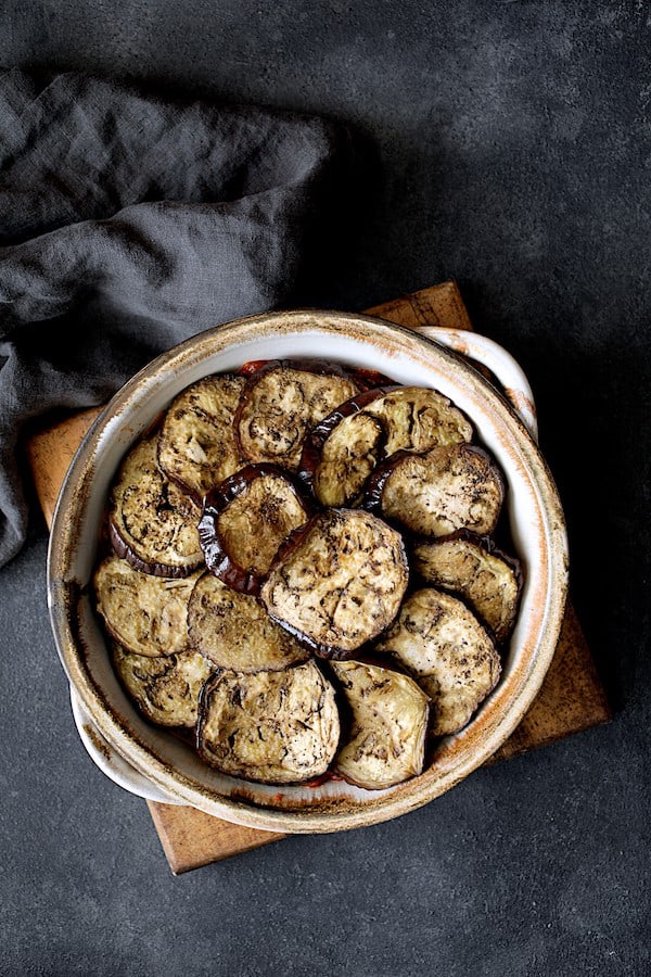 Photo of second layer of eggplant in clay baking dish.