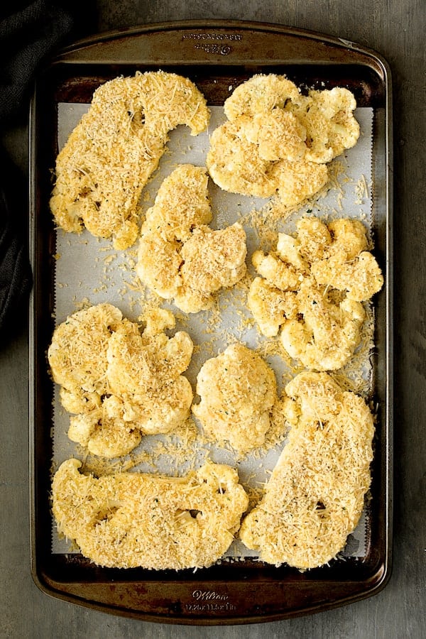 Photo of breaded cauliflower steaks on baking sheet before being baked.