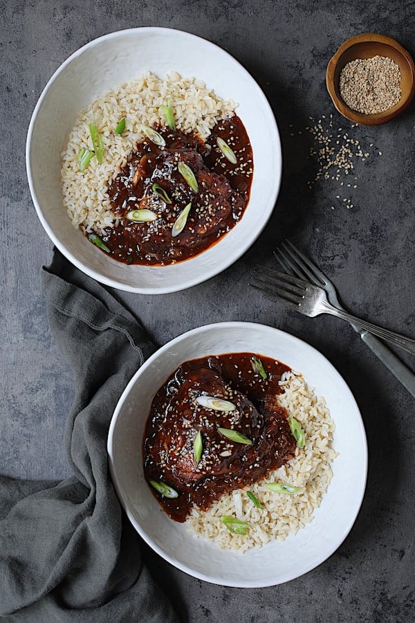 Photo of two servings of Korean Braised Chicken Thighs in white bowls on gray background.