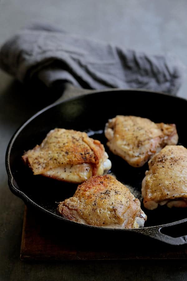 Photo of browned chicken thighs in cast iron skillet.