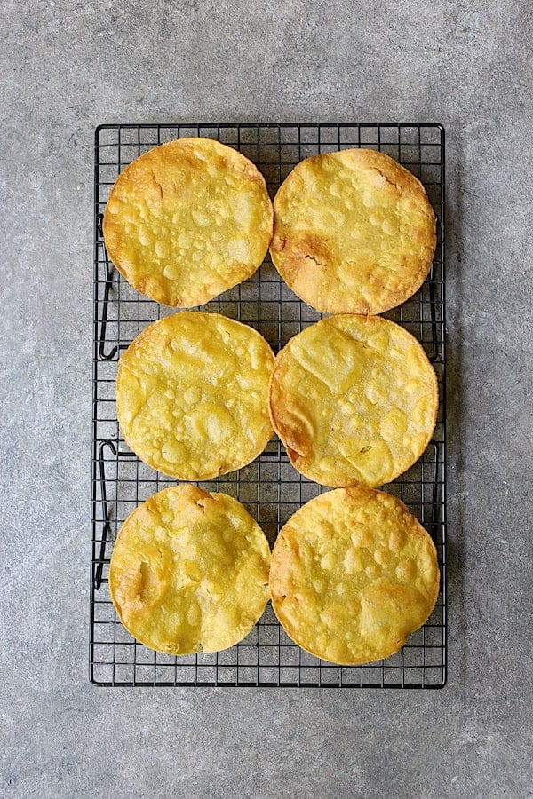 Photo of six fried tostada shells on cooling rack.