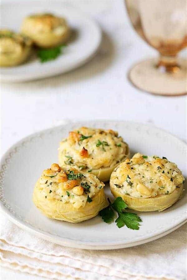 Three Lemon Parmesan Stuffed Artichoke Bottoms on white plate.