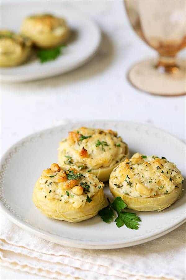 Photo of three Lemon Parmesan Stuffed Artichoke Bottoms on white plate.