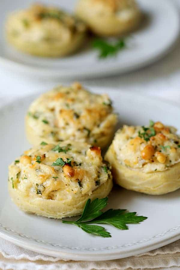 Close-up photo of three Lemon Parmesan Stuffed Artichoke Bottoms on white plate.