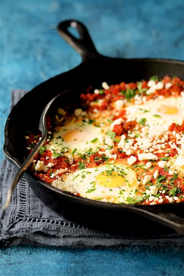 Close-up photo of Shakshuka with Red Lentils and Feta Cheese with in cast iron pan.