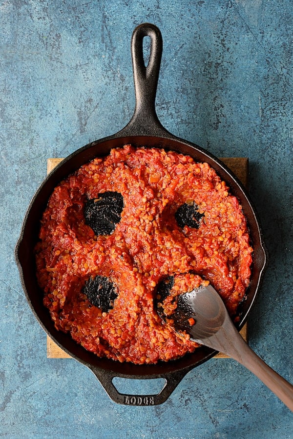 Photo of four wells in tomato and lentil mixture made with wooden spoon.