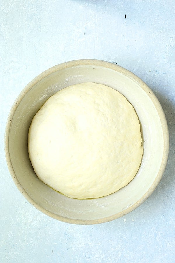Photo of risen focaccia dough in stoneware bowl.