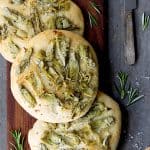Four Artichoke Foccacia with Rosemary on wood cutting board.