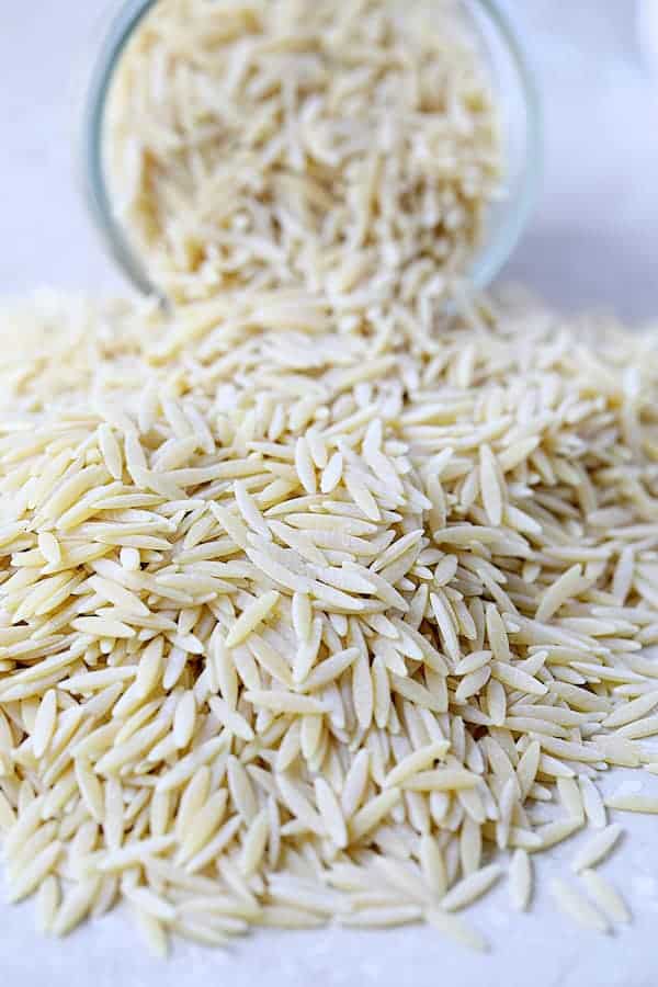 Photo of orzo pasta spilling out of a glass jar.