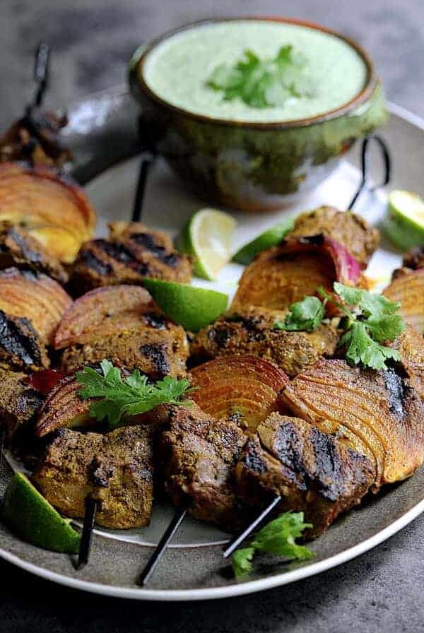 Four Indian-Style Beef Kabobs with Cilantro - Coconut Sauce on a gray-rimmed platter.
