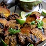 Four Indian-Style Beef Kabobs with Cilantro - Coconut Sauce on a gray-rimmed platter.