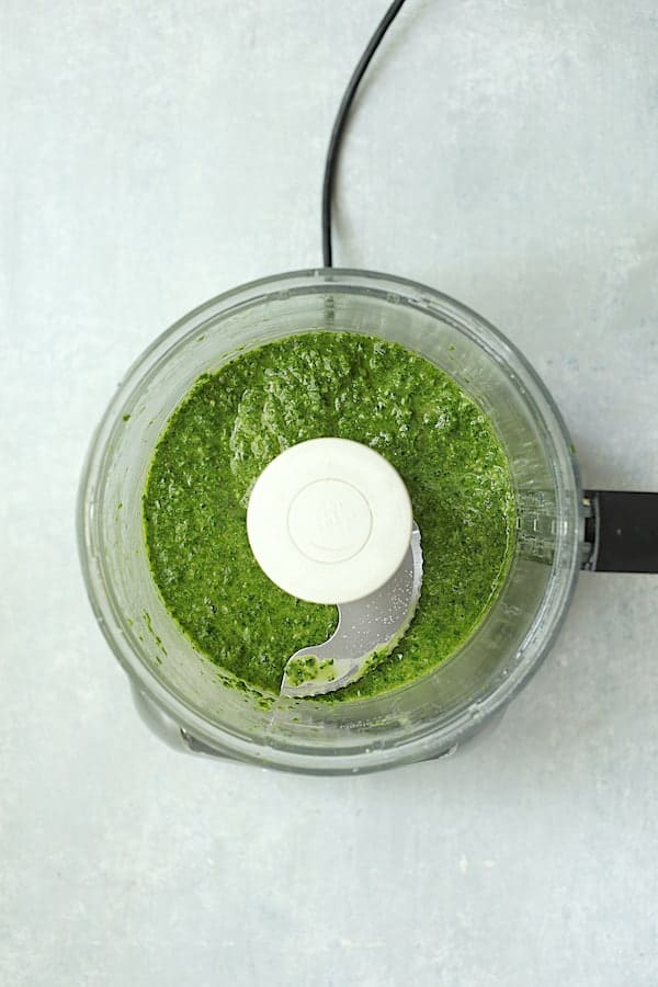 Photo of basil salsa verde in food processor.