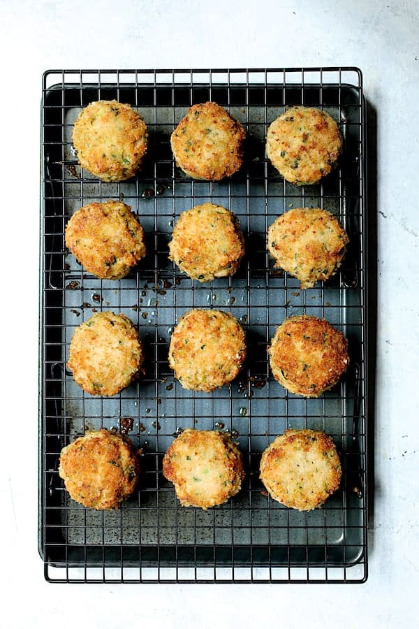 Photo of 12 fried shrimp cakes on cooling rack set on baking sheet to drain.