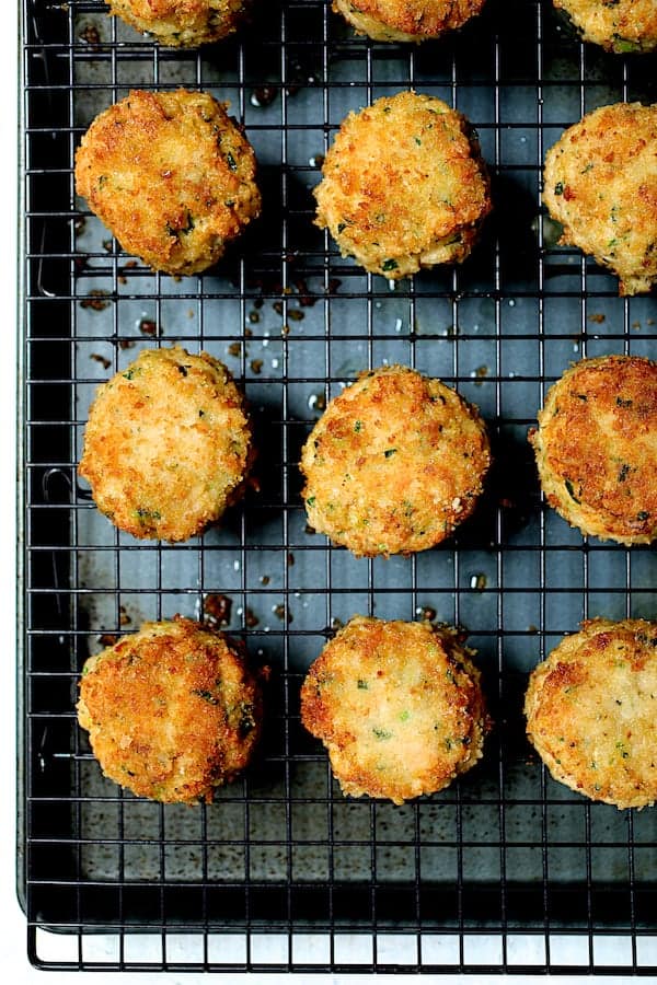 Close-up photo of cooked shrimp cakes on cooling rack set over baking sheet to drain.
