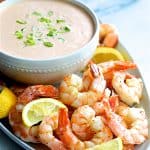 Shrimp Cocktail Louis on white platter with sauce garnished with lemon wedges.